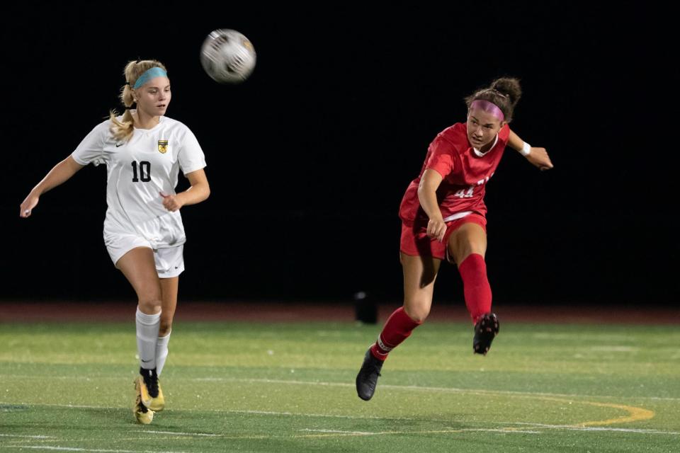 Central Bucks East Girls Soccer midfielder Sofia Mignon sends a ball to the outside wing, battling in the last few minutes of the big rival match against Central Bucks West on Monday, Aug. 29, 2022. It was the first night game under the newly constructed lights at Lt. Colby Umbrell Field at Patriot Stadium in Buckingham. In the last five minutes West broke a 2-2 tie, winning the match 3-2.