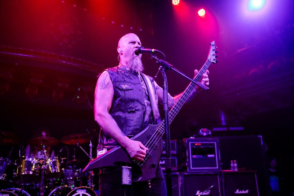 Steve Tucker of Morbid Angel plays a bass guitar and sings into a microphone