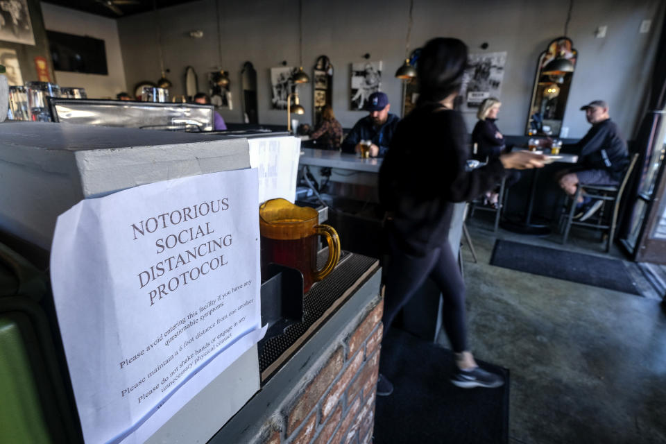 A notice, that reminds patrons to observe social distancing measures, is displayed at Notorious Burgers restaurant in Carlsbad, Calif., on Friday, Dec. 18, 2020. (AP Photo/Ringo H.W. Chiu)