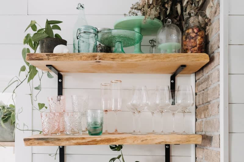 Wood shelves with glassware by exposed brick wall