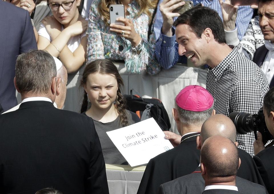 Pope Francis, partially seen at left, greets Swedish teenage environmental activist Greta Thunberg, center, during his weekly general audience in St. Peter's Square, at the Vatican, Wednesday, April 17, 2019. (AP Photo/Gregorio Borgia)