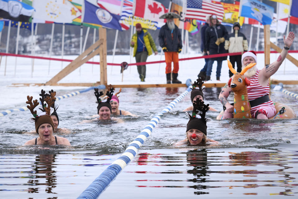 Swimmers, dressed as Santa and reindeer, take a lap during the 25 meter hat competition during the winter swimming festival on frozen Lake Memphremagog, Friday, Feb. 23, 2024, in Newport, Vermont. (AP Photo/Charles Krupa)