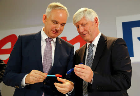 FILE PHOTO: Johannes Teyssen (L), chief executive office of E.On, and Rolf Martin Schmitz, chief executive officer of RWE AG, exchange pens with their respective company logos following a news conference after unveiling plans for an asset swap deal between the two German utilities in Essen, Germany March 13, 2018. REUTERS/Wolfgang Rattay/File Photo