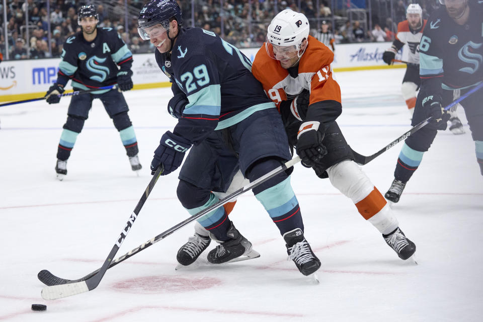 Seattle Kraken defenseman Vince Dunn (29) and Philadelphia Flyers right wing Garnet Hathaway (19) vie for the puck during the second period of an NHL hockey game, Friday, Dec. 29, 2023, in Seattle. (AP Photo/John Froschauer)