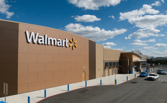 A Walmart storefront against a blue sky with white, fluffy clouds.