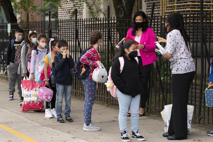 FILE —Teachers line up their students before entering PS 179 elementary school in the Kensington neighborhood, Sept. 29, 2020, in the Brooklyn borough of New York. New York City public school students will be allowed to remove their masks outside starting next week but must keep them on indoors for now. Schools Chancellor David Banks announced the new policy in a news release Friday, Feb. 25, 2022. (AP Photo/Mark Lennihan, File)