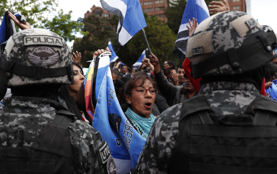 Police stand guard as supporters of Bolivian President Evo Morales, who is running for a fourth term, rally outside the Supreme Electoral Court where election ballots are being counted in La Paz, Bolivia, Monday, Oct. 21, 2019. A sudden halt in release of presidential election returns led to confusion and protests in Bolivia on Monday as opponents suggested officials were trying to help Morales avoid a risky runoff. (AP Photo/Juan Karita)