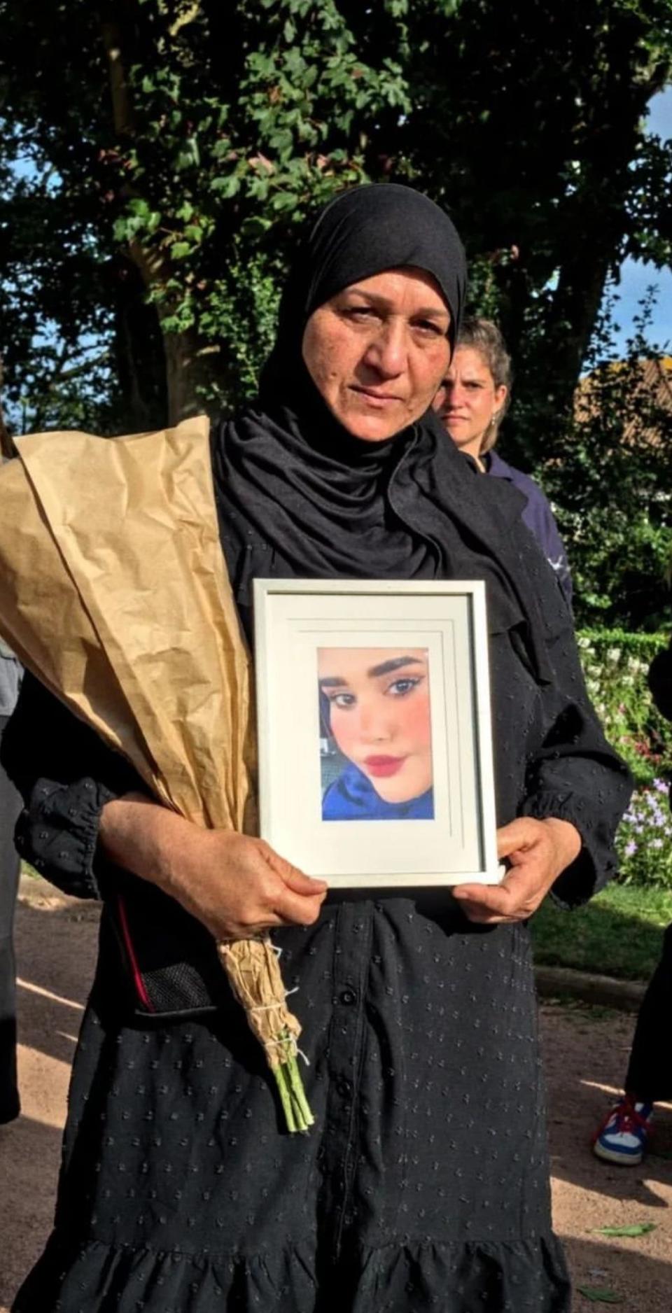 A black woman has a picture of a young woman with a black headscarf