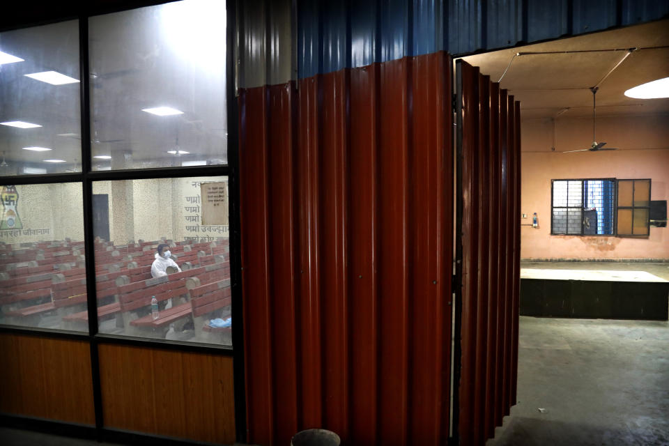 A man watches the cremation of his relative who died of COVID-19, in New Delhi, India, Monday, April 19, 2021. New Delhi imposed a weeklong lockdown Monday night to prevent the collapse of the Indian capital's health system, which authorities said had been pushed to its limit amid an explosive surge in coronavirus cases. (AP Photo/Manish Swarup)