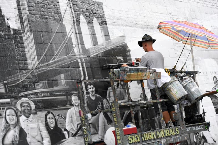 Liam Williams, artist at Colossal Media, paints an ad on the side of Colossal Media's office building in New York