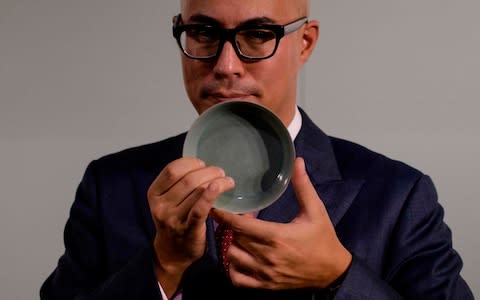 Nicolas Chow, Deputy Chairman for Sotheby's Asia, holds a Ru Guanyao brush washer bowl from China's Song Dynasty - Credit: AFP