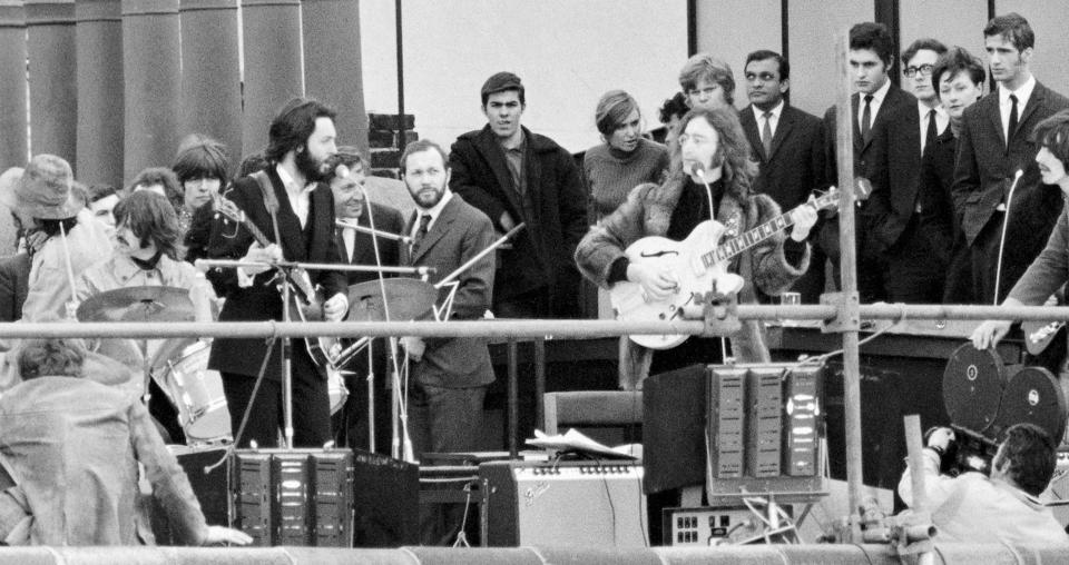 Performing on the rooftop among a crowd, from left to right: Ringo Starr, Paul McCartney, John Lennon and George Harrison. 