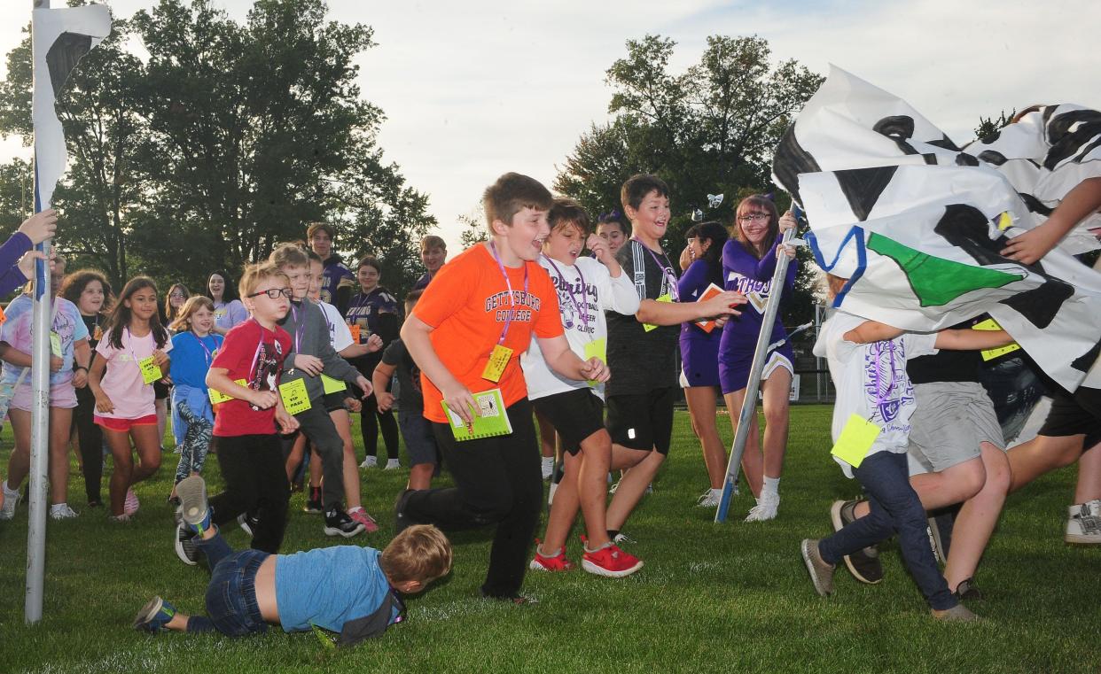 Children run through a paper banner that read "Let's Tackle Reading" during the Literacy Under the Lights event Saturday, Sept. 16, 2023, at Schaefer-Davies Stadium in Sebring.