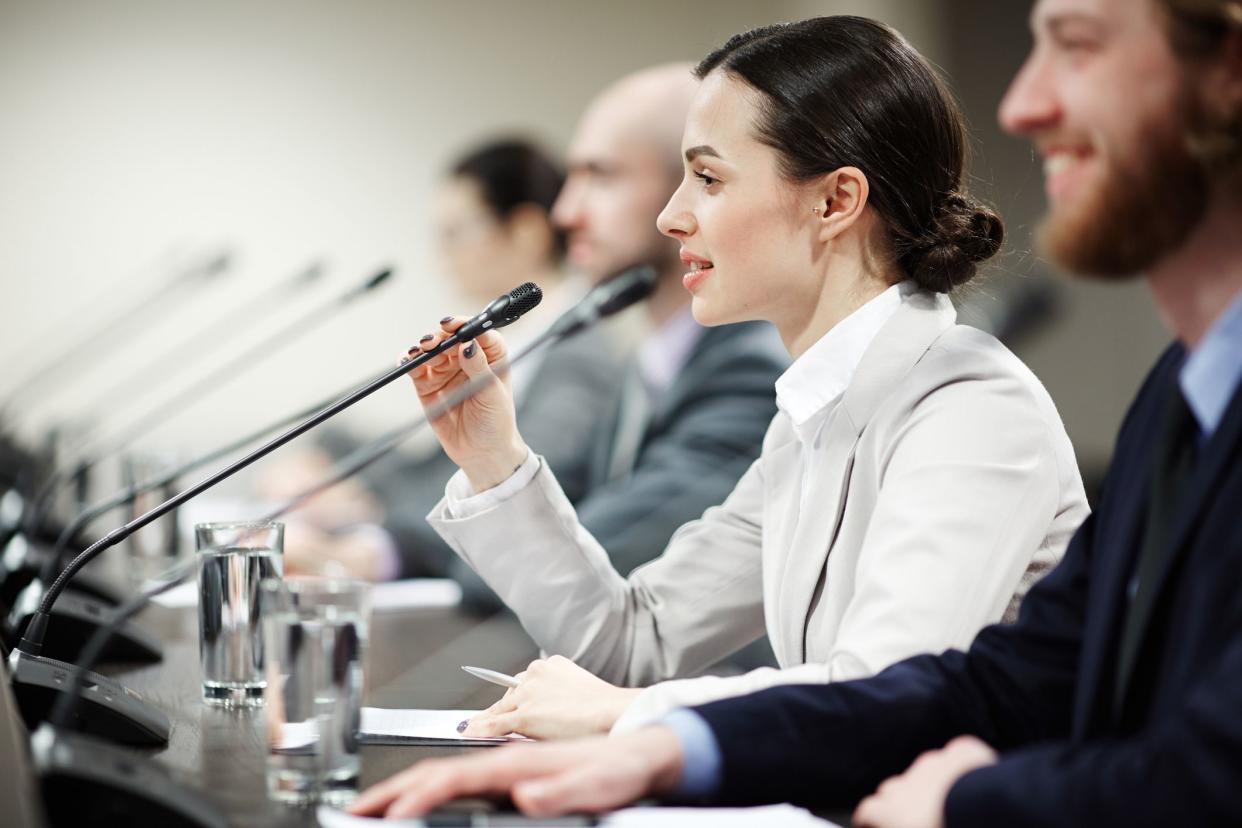 One of young politicians speaking in microphone among other participants of conference