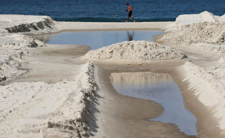 A man kicks a ball next to sewage system flowing on Copacabana beach in Rio de Janeiro, Brazil, June 9, 2016. REUTERS/Sergio Moraes