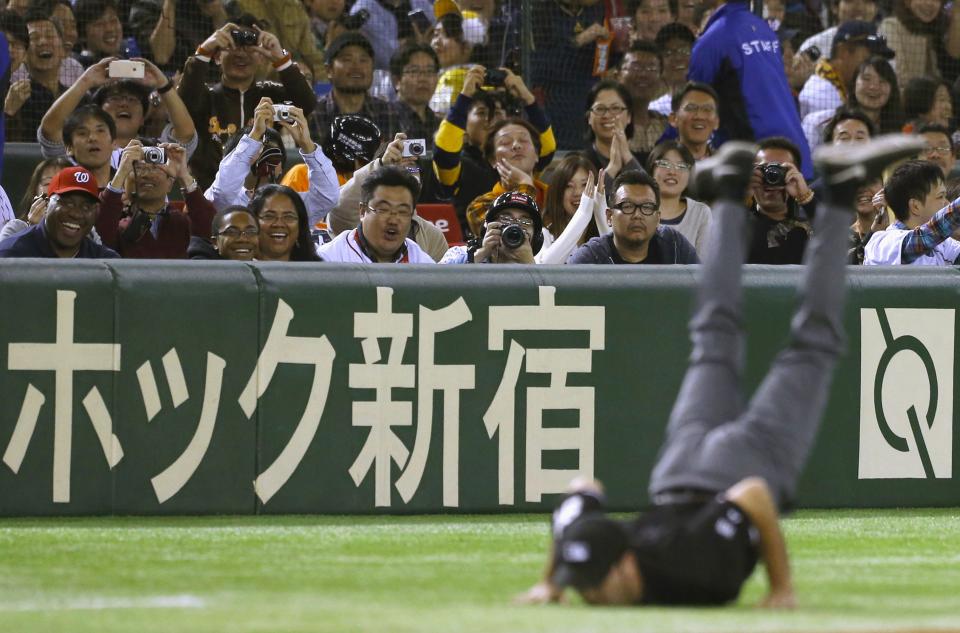 Fans look at a dance performance by third base umpire during the fourth inning of an exhibition baseball game between Japan and U.S. Major League Baseball (MLB) All-Stars in Tokyo, in this November 16, 2014 file photo. REUTERS/Yuya Shino/Files (JAPAN - Tags: TPX IMAGES OF THE DAY SPORT) BASEBALL)