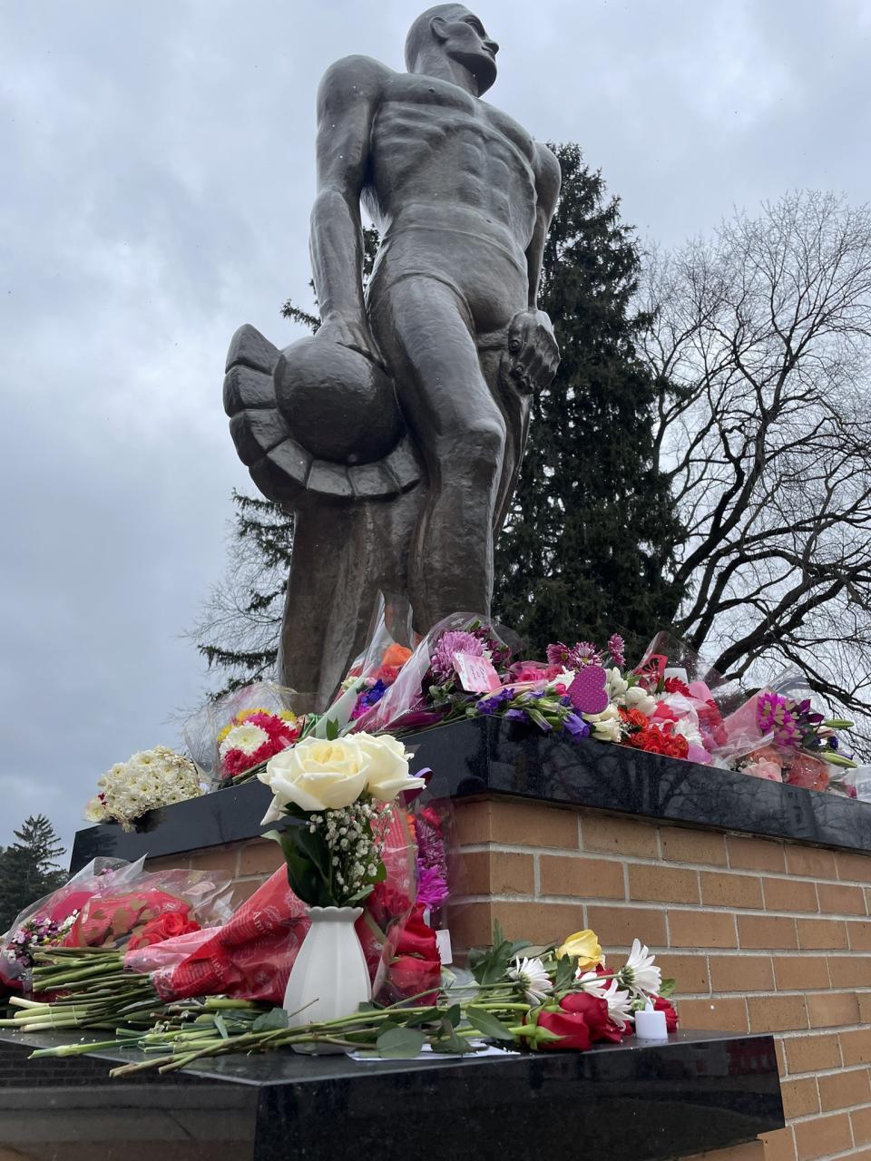 Flowers laid at the Spartan statue at Michigan State University mark one year since a deadly campus shooting. (Feb. 13, 2024)