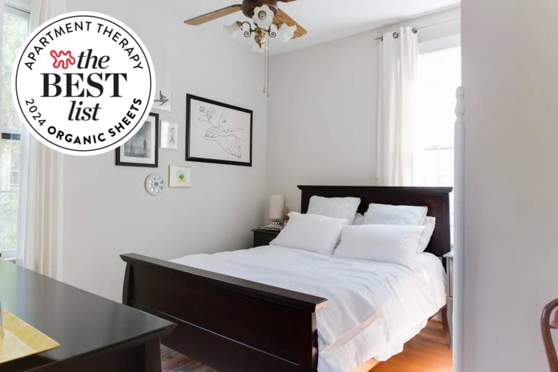 Photo of bed with white sheets, pillowcases, coverlet. White walls, wood ceiling fan, large window. There is a seal in the upper left that reads "Apartment Therapy The Best List: 2024 Organic Sheets"
