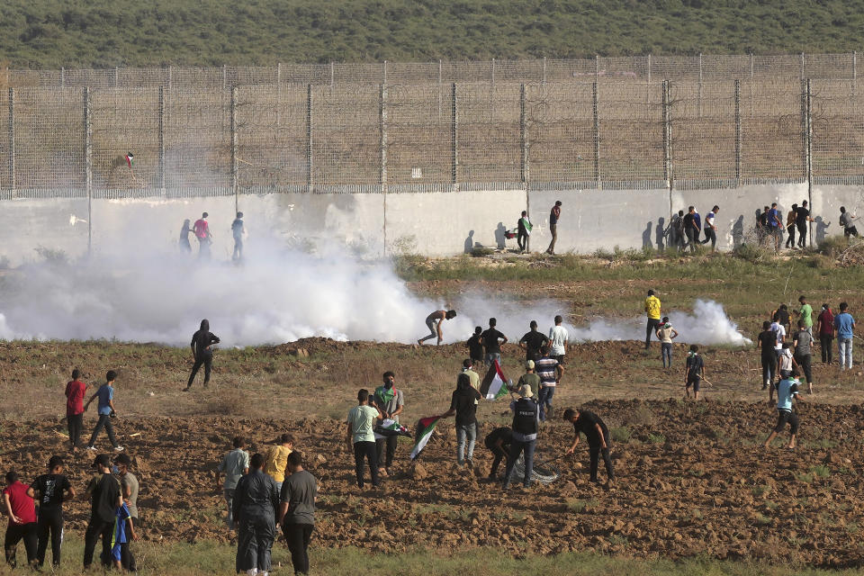 Palestinian protesters try to cover from tear gas during clashes with Israeli troops, along the frontier with Israel, east of Gaza City, Monday, Aug. 21, 2023. Hundreds of Palestinians protested near the border fence with Israel. (AP Photo/Adel Hana)
