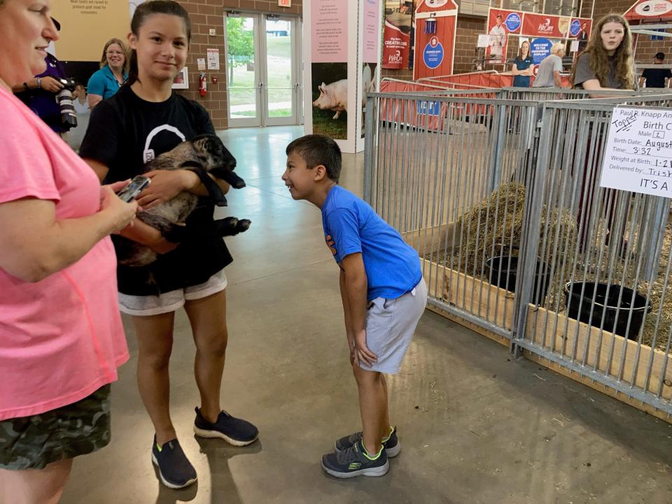 Benjamin and Alexandra Ocampo play with a lamb at the "Cuddles & Snuggles Chore Time" event at the Iowa State Fair August 17.