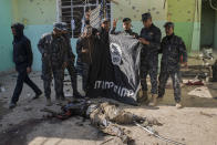 <p>Iraqi Federal Police officers hold up a captured ISIS flag next to a dead Islamic fighter in the ISIS held village of Abu Saif, 6 kilometres from Mosul on Feb. 22, 2017 in Nineveh, northern Iraq. (Photo: Martyn Aim/Getty Images) </p>