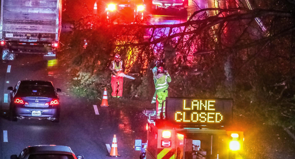 Authorities work to clear a fallen tree that is blocking a lane on I-20 at Langhorn Street in Atlanta on Thursday morning, Oct. 29, 2020. Tropical Storm Zeta sped across the Southeast on Thursday, leaving a trail of damage and more than 2 million homes and businesses in the dark in Atlanta. (John Spink/Atlanta Journal-Constitution via AP)