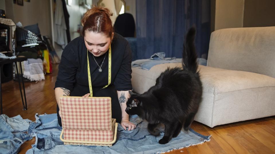 a person starts a sewing project next to a fluffy black cat