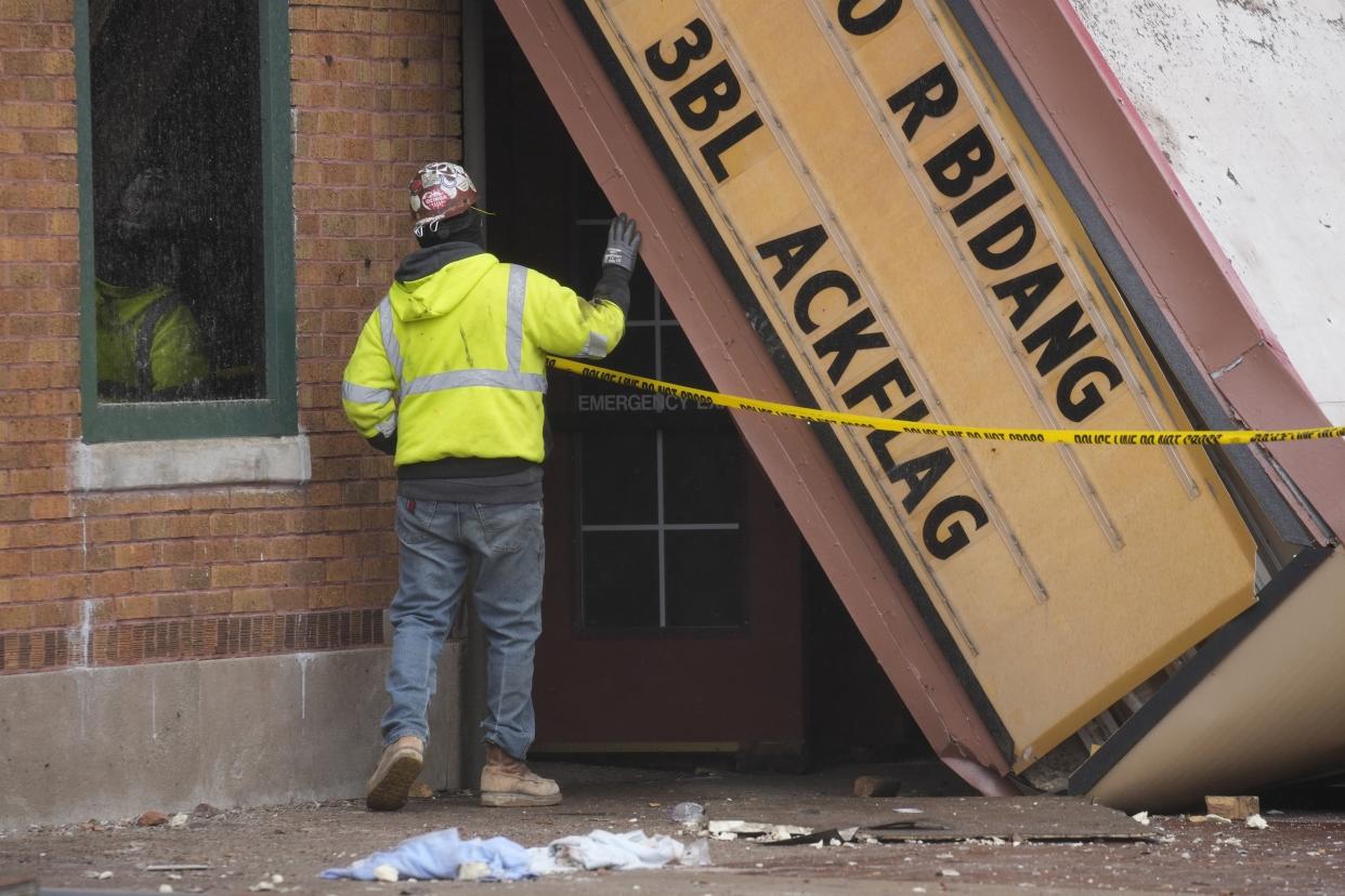 A worker inspects the collapsed marquee at the scene where the roof of the Apollo Theatre collapsed during a tornado, Saturday, April 1, 2023, in Belvidere, Ill. Belvidere Fire Chief Shawn Schadle said 260 people were in the venue. (AP Photo/Erin Hooley)