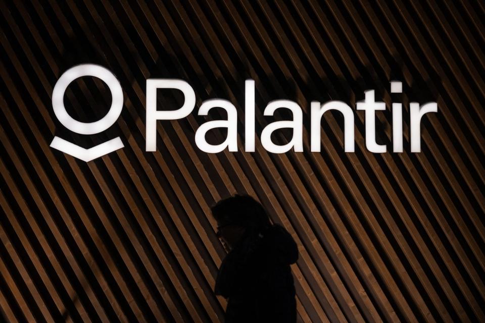 A person's silhouette under the Palantir logo.