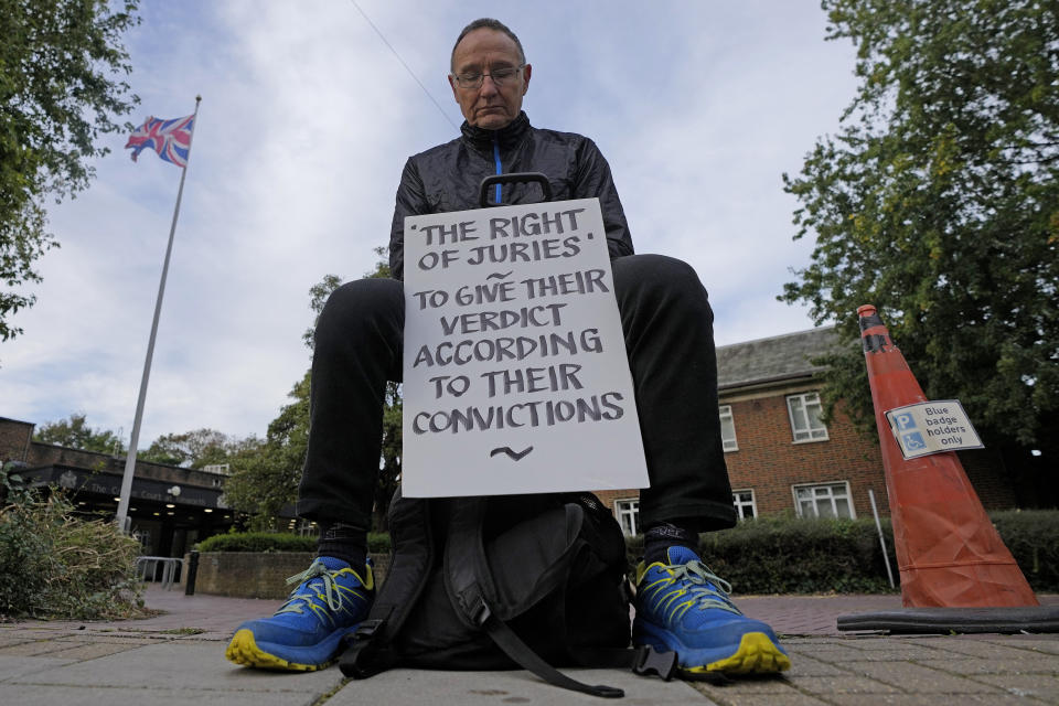 A protestor shows a placard as he sits outside the entrance to Isleworth Crown Court in London, Friday, Oct. 6, 2023. Britain is one of the world's oldest democracies, but some worry that essential rights and freedoms are under threat. They point to restrictions on protest imposed by the Conservative government that have seen environmental activists jailed for peaceful but disruptive actions. (AP Photo/Frank Augstein)