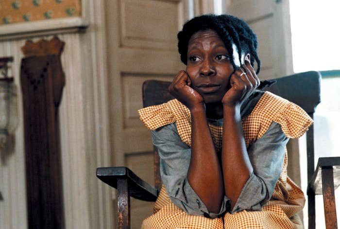 Whoopi Goldberg as Celie in a pensive moment in a scene from the movie "The Color Purple," sitting on a chair with her chin resting on her hands