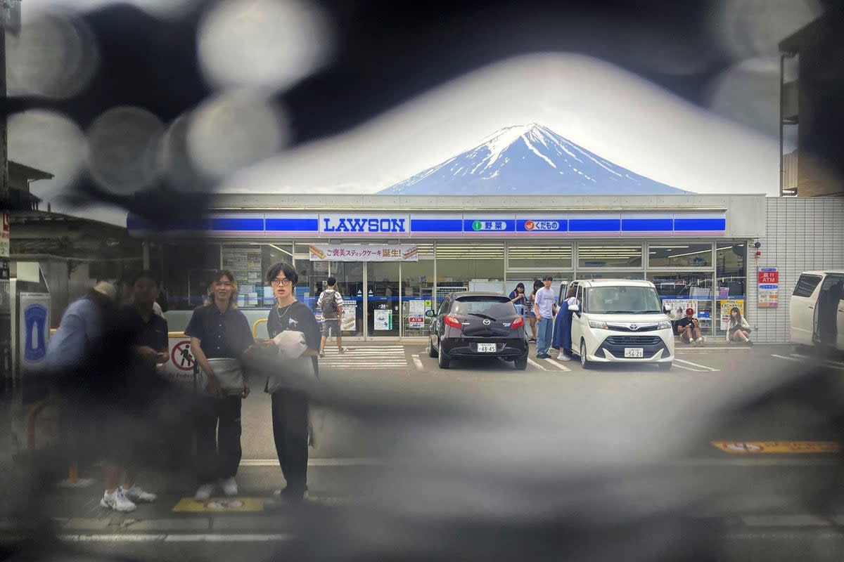 Mt Fuji is seen through a hole on a black screen installed across from a convenience store in Fujikawaguchiko town (AP)