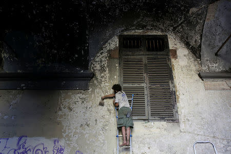 A member of the "Assemblea Cavallerizza 14:45" movement scrapes a wall at the Cavallerizza Reale building, which is occupied by the movement in Turin, Italy, July 15, 2016.REUTERS/Marco Bello