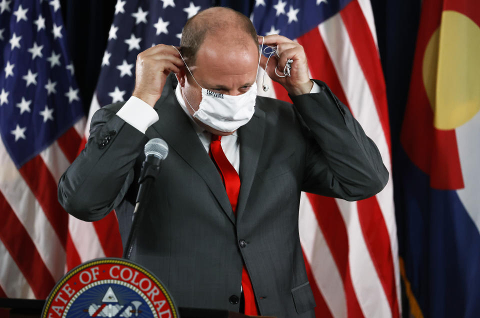 Colorado Governor Jared Polis puts on his face covering after a news conference to update the state's status in dealing with the new coronavirus Tuesday, July 28, 2020, in Denver. (AP Photo/David Zalubowski)