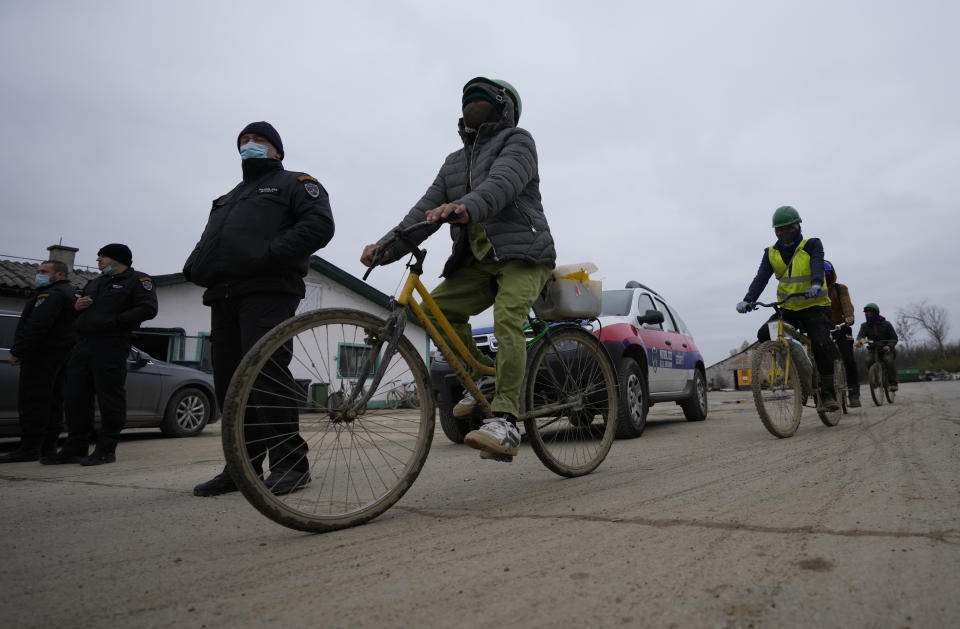 Vietnamese workers who are helping construct the first Chinese car tire factory in Europe ride bicycles past security officers near the northern Serbian town of Zrenjanin, 50 kilometers north of Belgrade, Serbia, Thursday, Nov. 18, 2021. Reports have emerged in Serbia of prison-like conditions for some 500 of them at the construction site in north of the country where China's Shandong Linglong Tire Co is building the huge factory. Populist-run Serbia is a key spot for China's expansion and investment policies in Europe and Chinese companies have kept a tight lid on their projects in the country amid reports of disrespect of the Balkan nation's anti-pollution laws and labor regulations. (AP Photo/Darko Vojinovic)