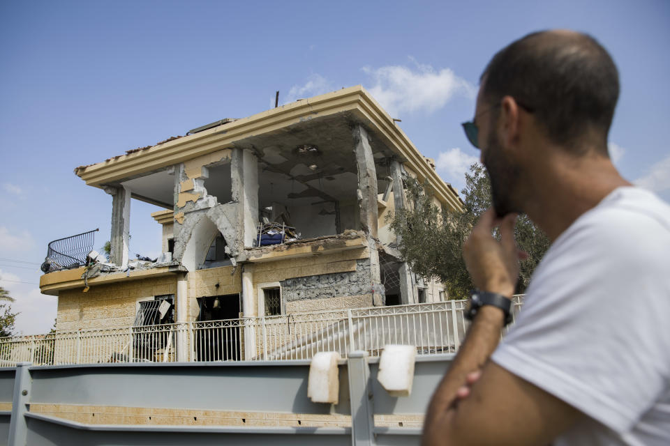 A man watches a house that was hit by a missile fired from Gaza Strip, in the city of Beersheba, southern Israel, Wednesday, Oct. 17, 2018. A medical service said a woman and her three children, whose home was struck, were being treated for shock after they fled to their shelter upon being awoken by warning sirens. (AP Photo/Tsafrir Abayov)