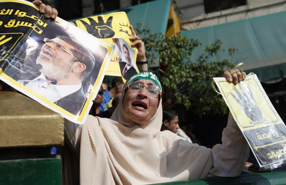 Supporter of ousted Egyptian president Mohamed Mursi cries while holding his poster and a "Rabaa" poster outside the Egyptian High Court in Cairo