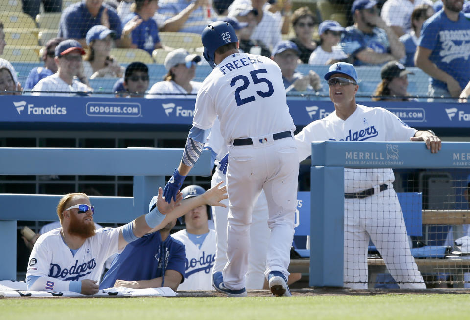 Los Angeles Dodgers' David Freese, center, is congratulated by Justin Turner, left, and coach Bob Geren, right, after scoring on a bases-loaded walk during the first inning of a baseball game against the Chicago Cubs in Los Angeles, Sunday, June 16, 2019. (AP Photo/Alex Gallardo)