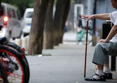 An elderly man rests beside a street in downtown Beijing