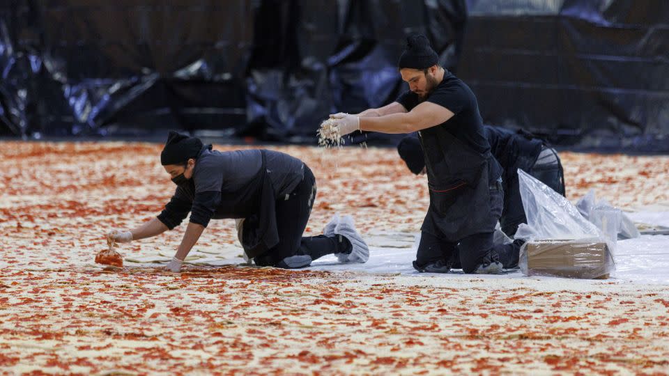 Cooks work inside the Los Angeles Convention Center on January 18, 2023, to create the world's largest pizza. - Mike Blake/Reuters