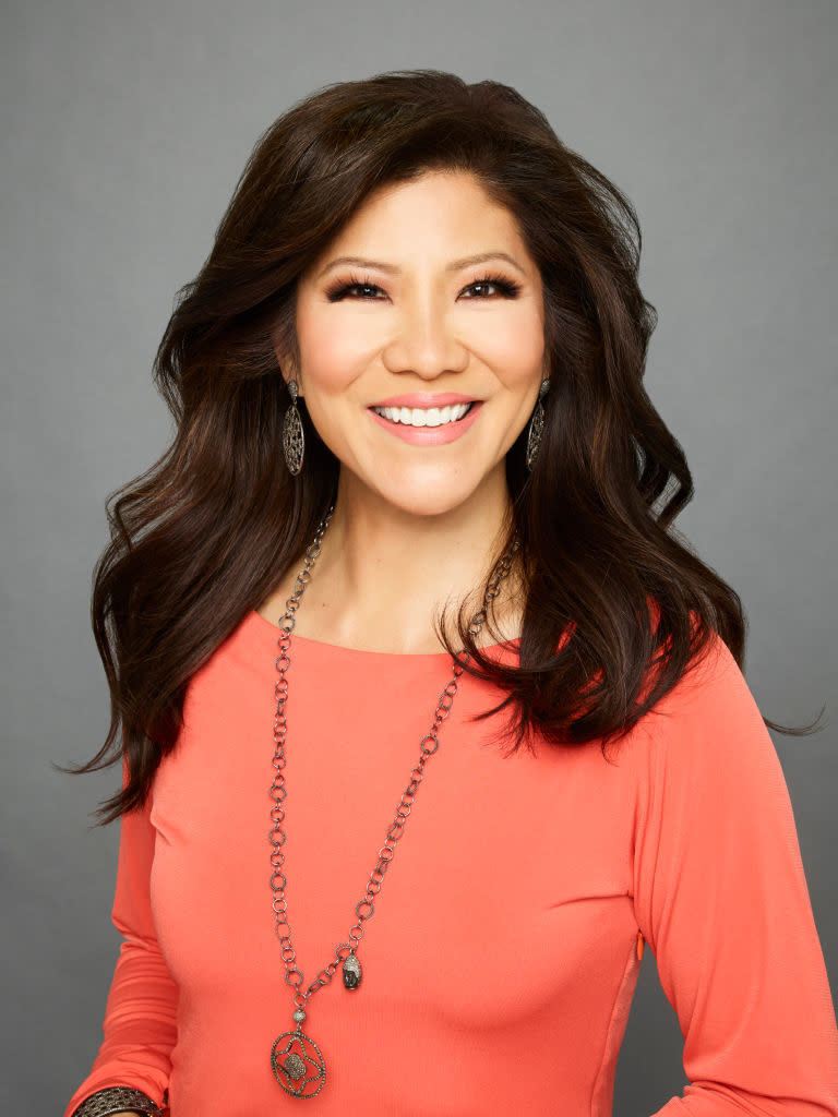 Julie Chen smiles in a bright top with a long necklace and earrings