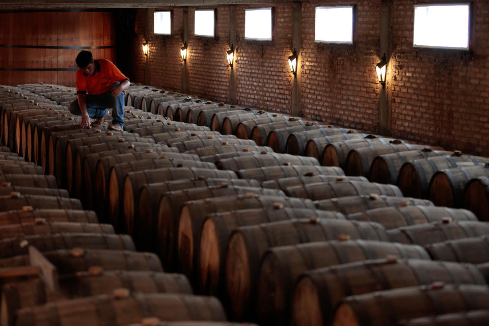In this April 5, 2013 photo, a worker inspects oak barrels in a cellar used for aging cachaça, Brazil's national spirit, at the Alambique Cambeba in Alexania, Goias state, Brazil. Made from sugarcane, cachaca has always been sold in the United States under the label “Brazilian rum,” but a recent decision by the U.S. Treasury's Alcohol and Tobacco Tax and Trade Bureau allows for it to be commercialized under its Portuguese name. (AP Photo/Eraldo Peres)