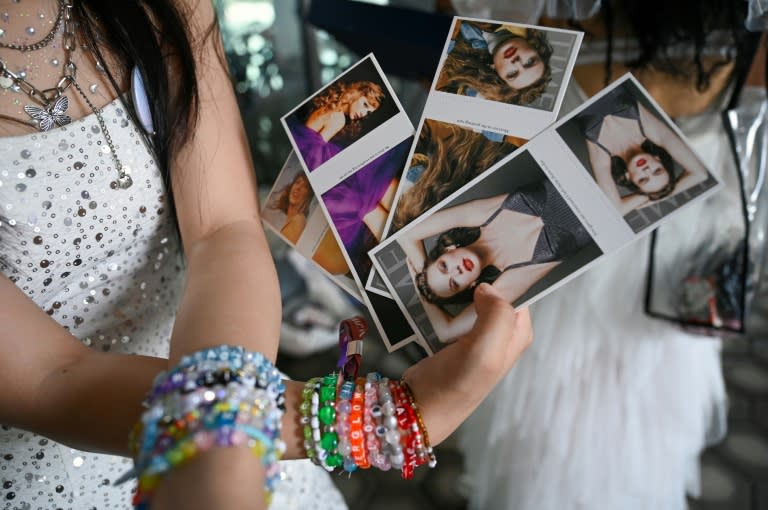 Una fan de Taylor Swift, sostiene unas postales de la cantante estadounidense antes de su concierto de la gira Eras Tour en el Estadio Nacional Stadium de Singapur el 7 de marzo de 2024 (Roslan Rahman)