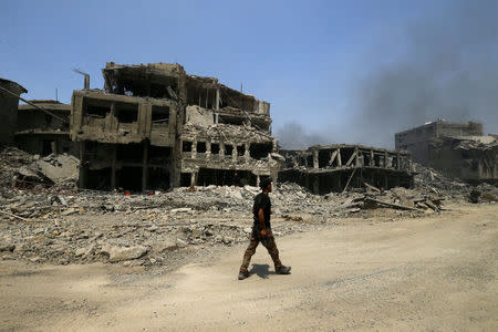 A member of Iraqi Counter Terrorism Service (CTS) walks along destroyed buildings from clashes in the Old City of Mosul, Iraq July 10, 2017. REUTERS/Thaier Al-Sudani