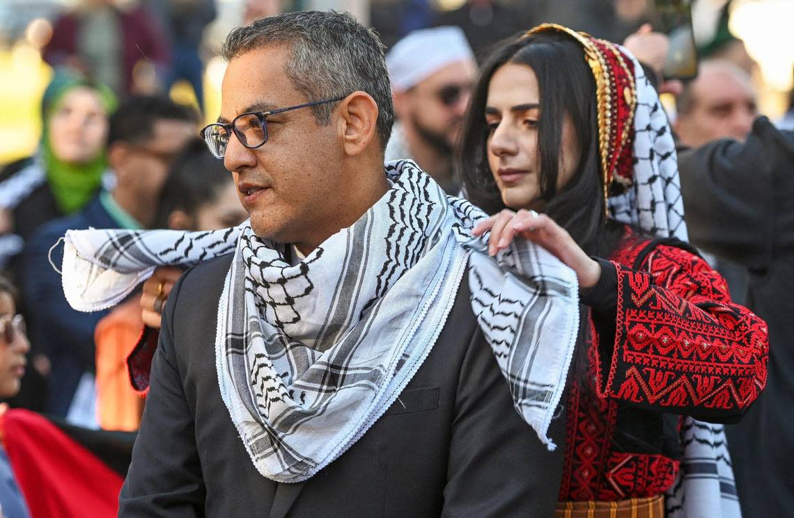 Layla Darwish of the Palestinian Freedom Project adjusts a traditional keffiyeh, or scarf, around the neck of Fresno City Councilmember Miguel Arias before a City of Fresno-sponsored ceremony to raise the flag of Palestine to show support for the Palestinian community as war rages on in the Middle East, in Eaton Plaza on Friday, Dec. 8, 2023.