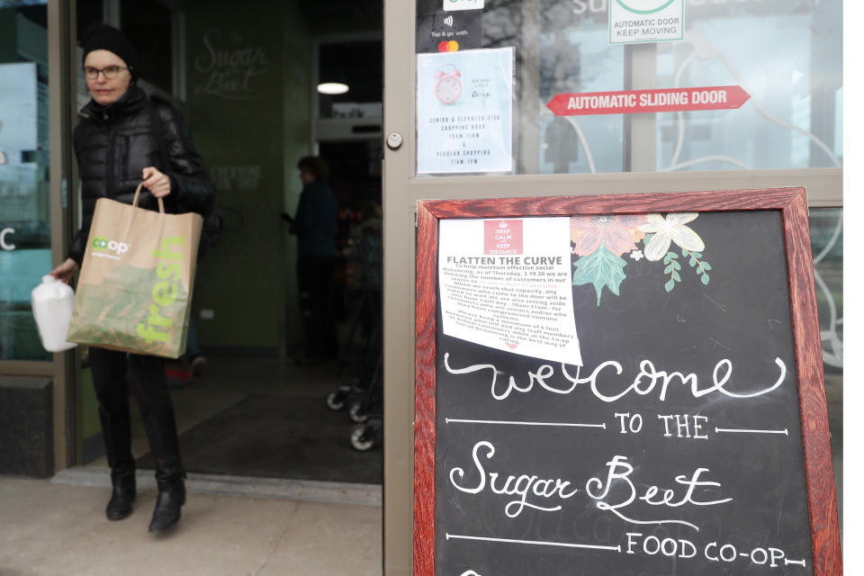 A shopper at the Sugar Beets Food Co-Op in the Village of Oak Park, Ill., leaves the store during a time frame dedicated to older shoppers Friday, March 20, 2020. There are at least three confirmed cases of COVID-19 in Oak Park, just nine miles from downtown Chicago, where the mayor has ordered residents to shelter in place. With so few tests available, surely there are others, says Tom Powers, spokesman for the village of about 52,000 in a metropolitan area with millions. (AP Photo/Charles Rex Arbogast)