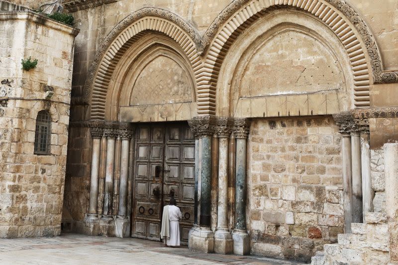 A worshipper stands in front of the locked door of Jerusalem's Church of the Holy Sepulchre amid coronavirus restrictions in the walled Old City