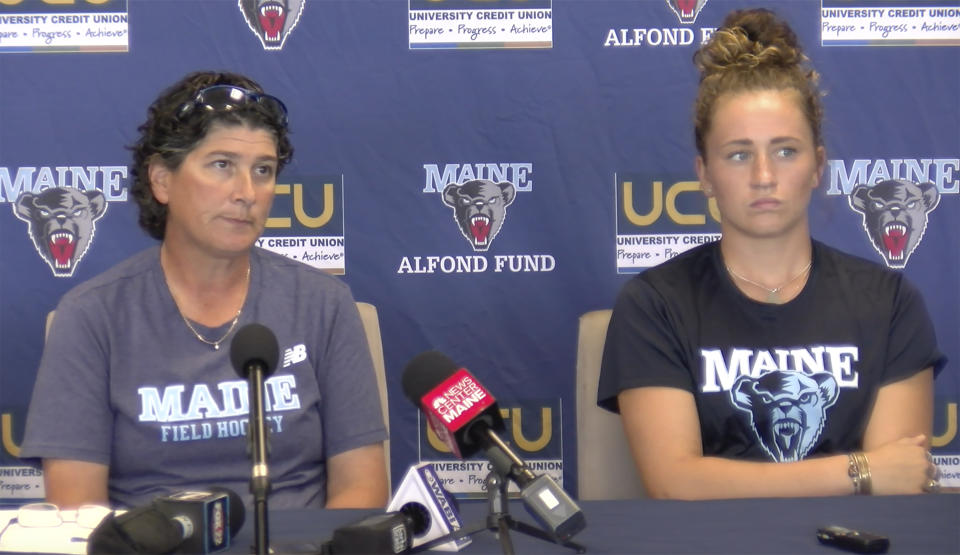 University of Maine field hockey head coach Josette Babineau, left, and senior team captain Riley Field are shown during a press conference on Monday, Sept. 9, 2019, in Orono, Maine. After the shock wore off of halting a women's field hockey game in the middle of overtime just so they could shoot off fireworks for a football game that hadn't even started, the captain of the Maine team said it's par for the course when you're a female athlete. Indeed, for all the advances created by Title IX, there's still an awful lot of hearts and minds that still need changing. (University of Maine Athletics via AP)