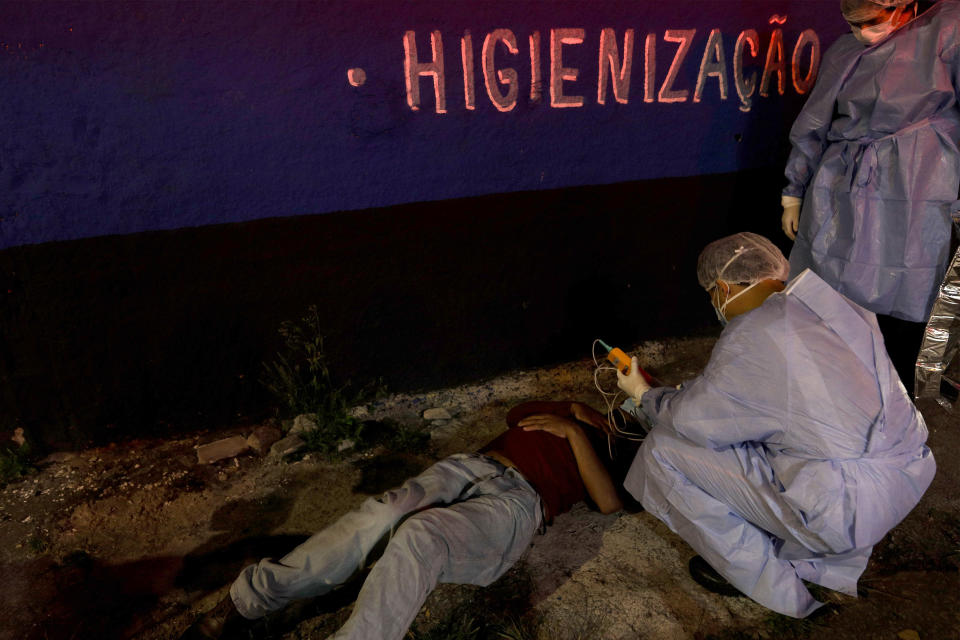 FILE - In this May 8, 2021 file photo, a man suspected of having COVID-19 who collapsed on a street is treated by Mobile Emergency Care Service staff, in Sao Paulo, Brazil. Nearly 2,000 people are dying of COVID-19 each day of in Brazil, a tally surpassed only by India. (AP Photo/Marcelo Chello, File)