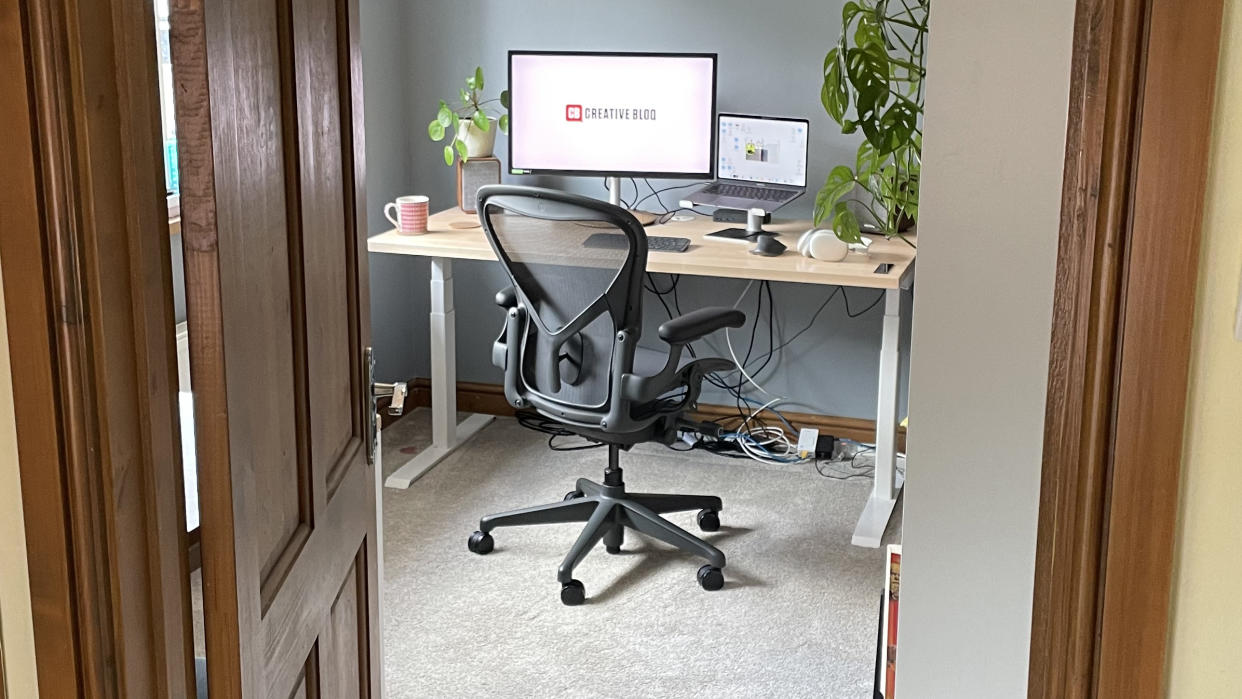  A photo through a doorframe, showing an office set up, including the Herman Miller Aeron chair.  